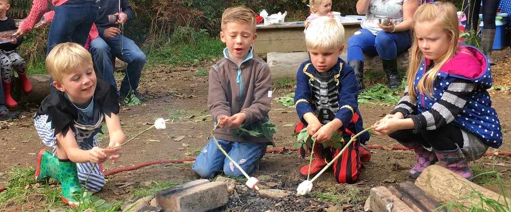 Children toasting marshmallows around campfire 