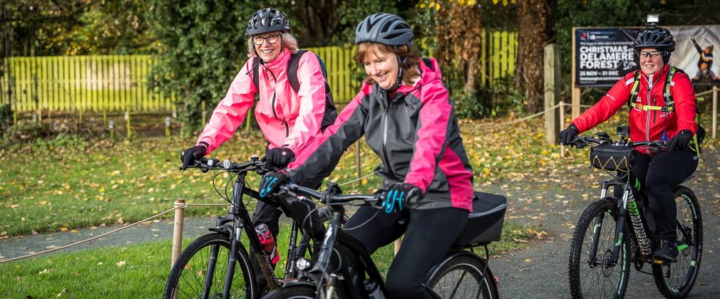 Three women ride bikes