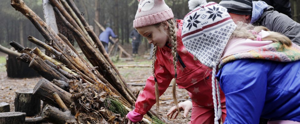 Children building a den out of sticks in a forest