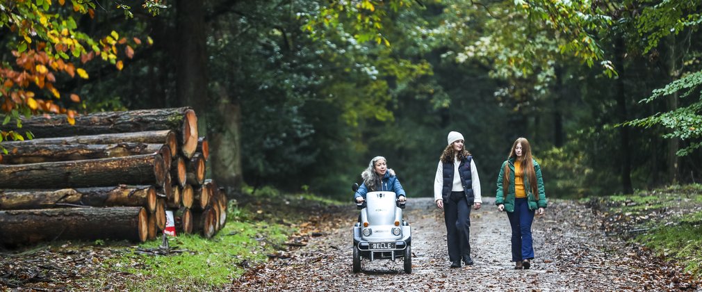 Woman using a tramper with two walkers in the forest