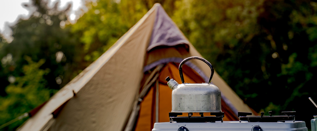A kettle on a hob in front of a tent