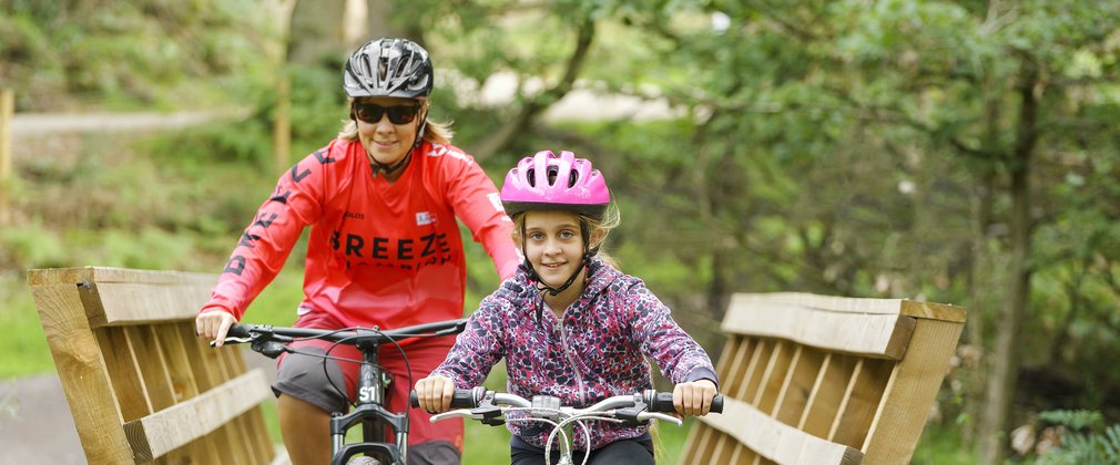 Woman and girl cycling over bridge