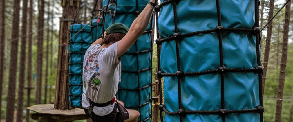 person climbing on ropes activity in forest