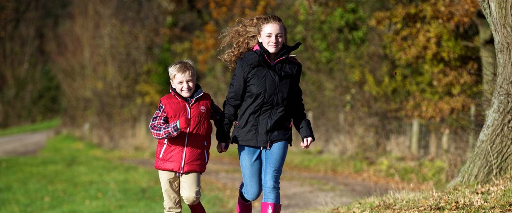 Children running on muddy forest path in wellies