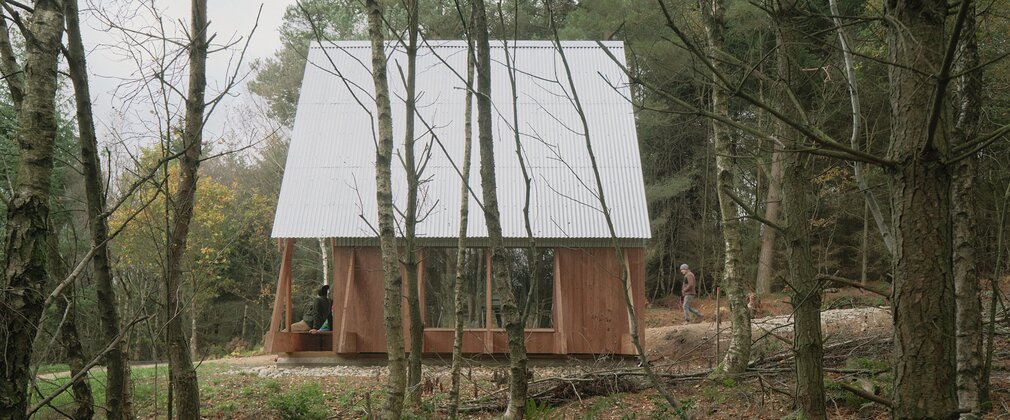 A timber constructed structure with a metal roof in the forest