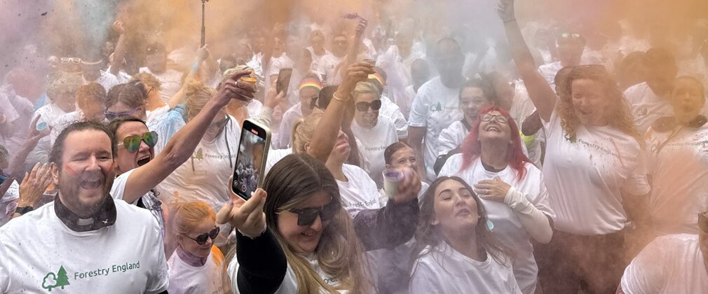 A group of people in white t shirts with clouds of paint in the air