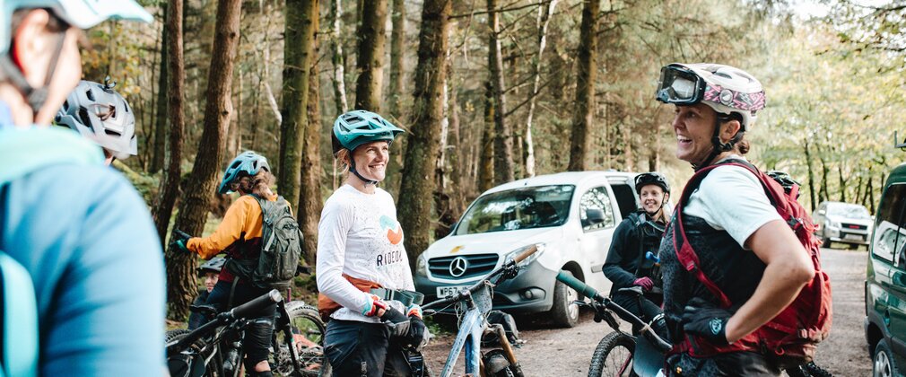 Female mountain bikers standing next to bikes having a happy chat before a race.