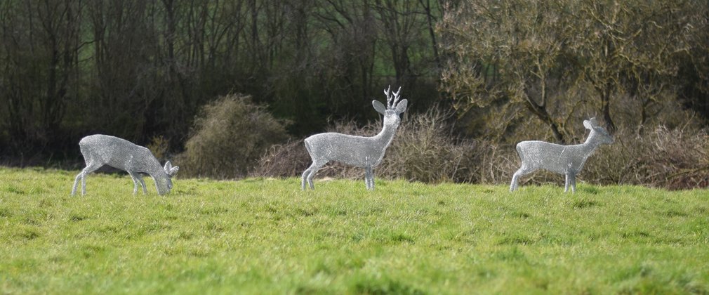 3 wire deer sculptures in a field