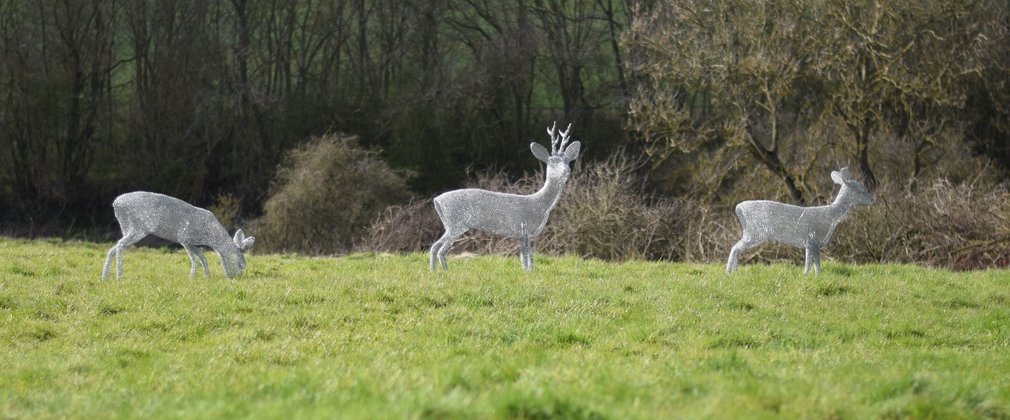 3 wire deer sculptures in a field