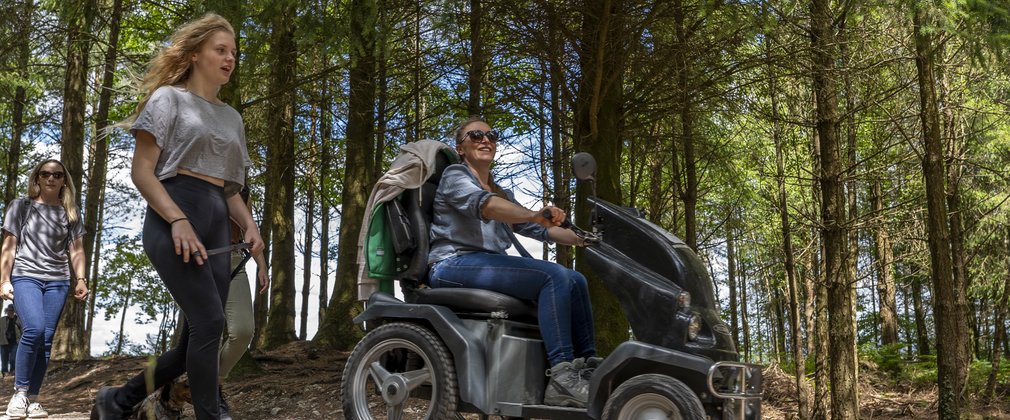 A woman is riding a Tramper next to a walker