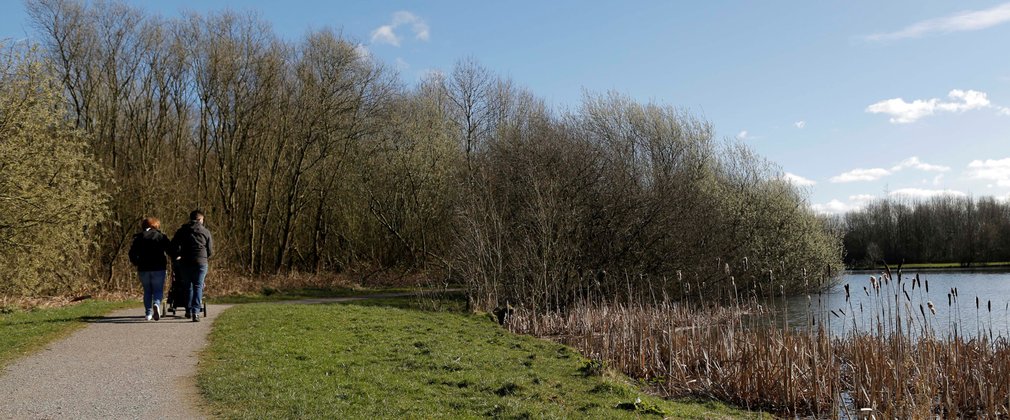 Couple walking next to pond on sunny day 