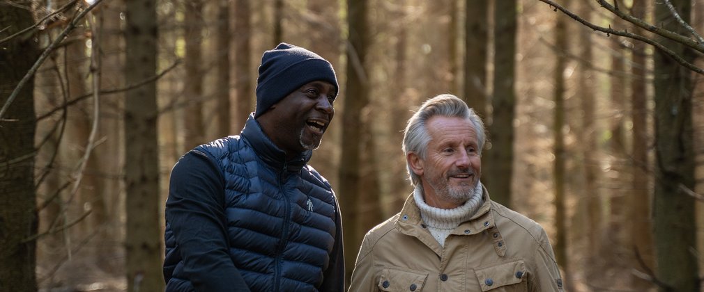 Two men smiling while walking in the forest