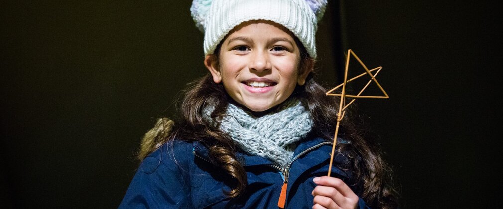 A young girl holds up a wooden stick star that she has created