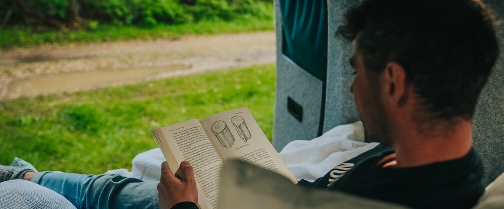 A man reading a book in a campervan