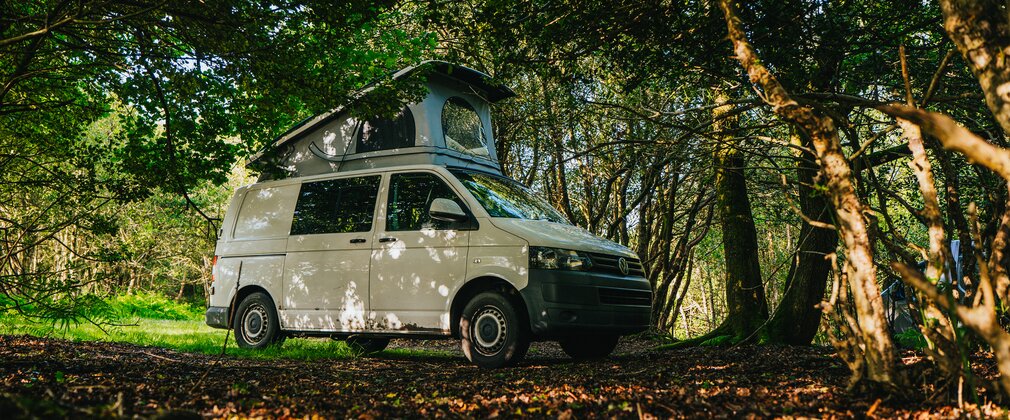 A white camper van surrounded by trees