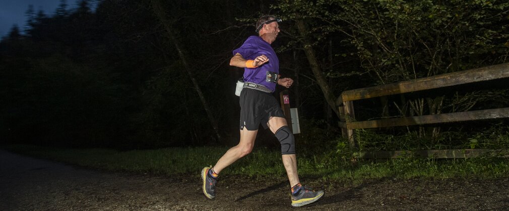 A runner taking part in a race through the forest at night