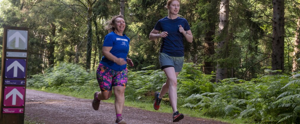 Two women running through a fores