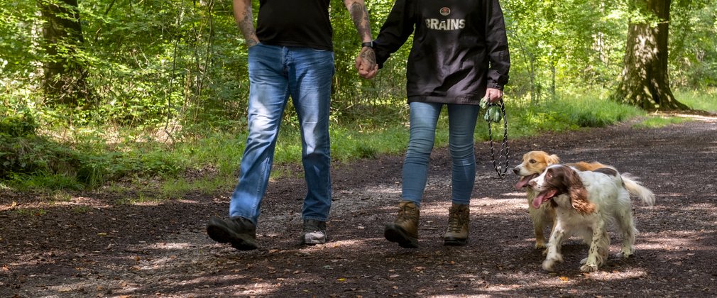 Two walkers in jeans and black tops walking with two spaniels