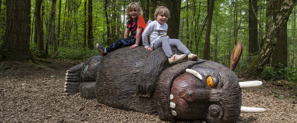 Two children sitting on a Gruffalo sculpture