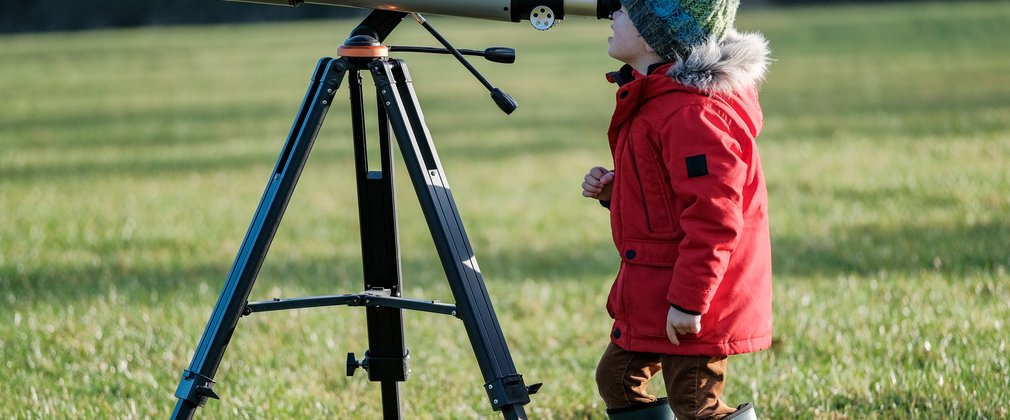 Child in red coat looking through telescope 2