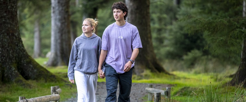 A couple walking along a surfaced forest trail