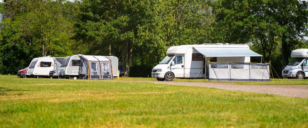 Motorhomes and caravans parked at Fineshade Wood campsite with awnings outside