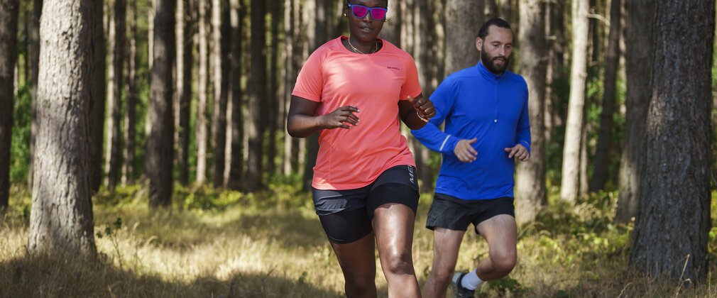 A woman and man running through the forest