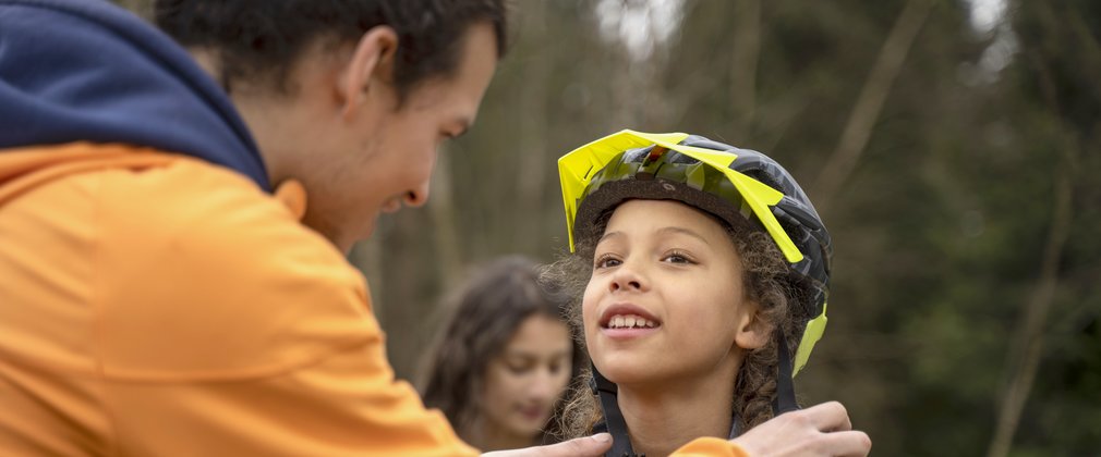 Dad helping child put cycling helmet on