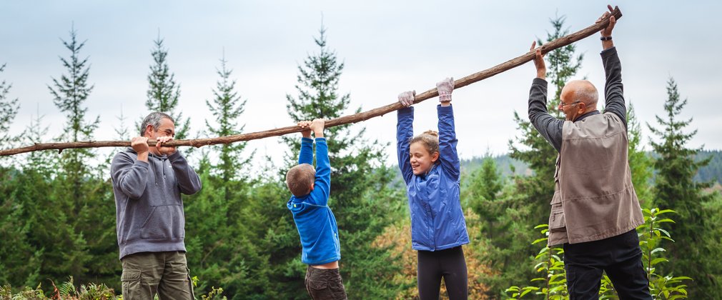 Family lifting branch and playing in front of forest landscape