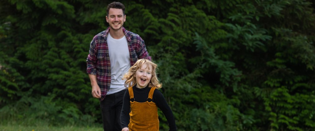 Child happily play running through grass 