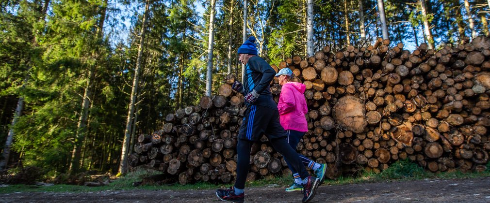 Two runners alongside timber stack