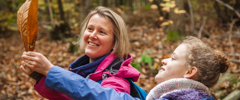 A woman and child looking at leaves they have found