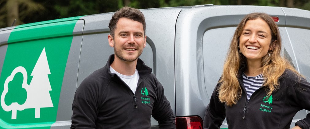 Group of Forestry England staff stood smiling in front of grey Forestry England van