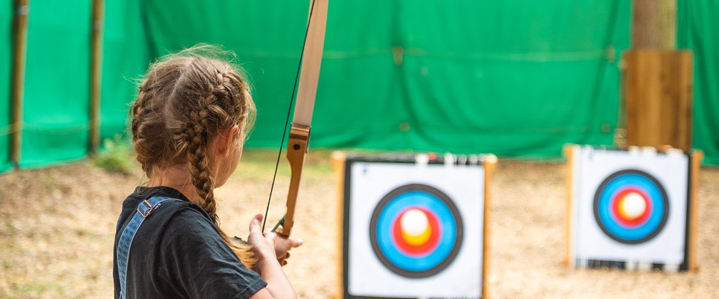 girl aims for target at archery