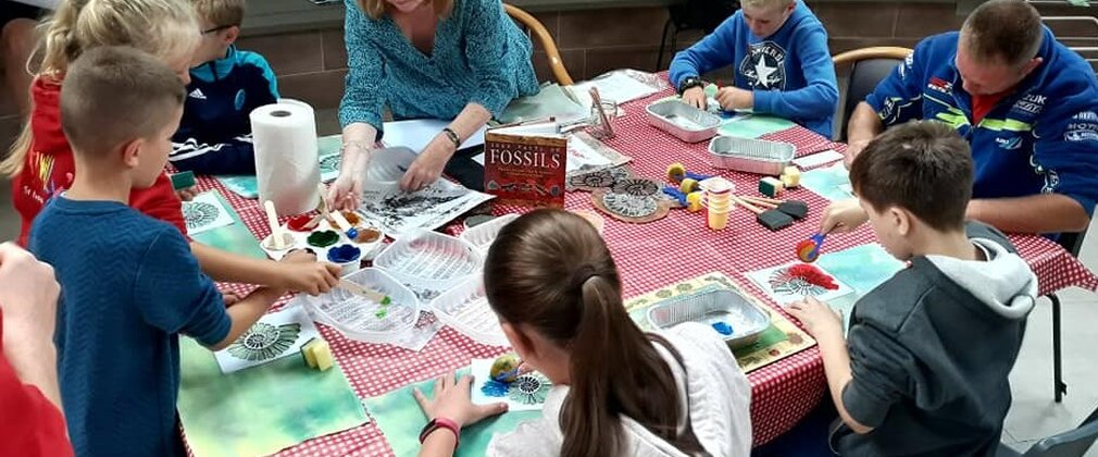 Children taking part in a fossil craft activity on a square table
