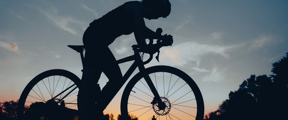 Silhouette of woman cycling at sunset