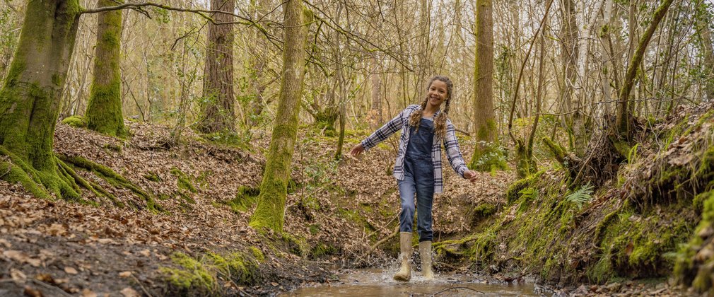Girl walking through muddy puddle in the forest