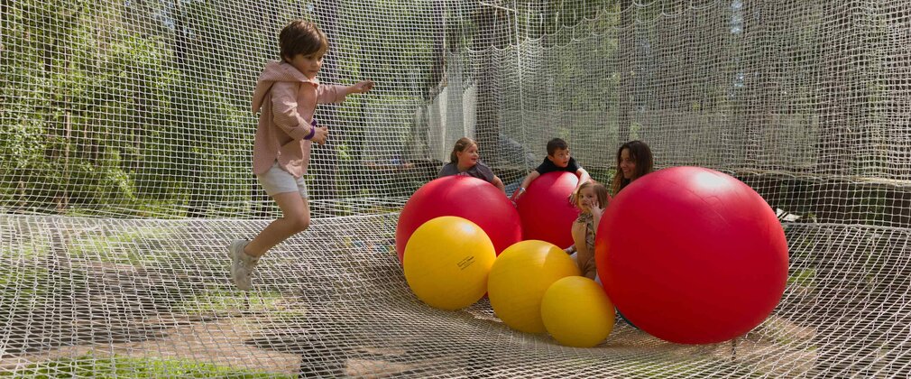 Four children and an adult in the Nets enclosure with large red and yellow inflatable balls