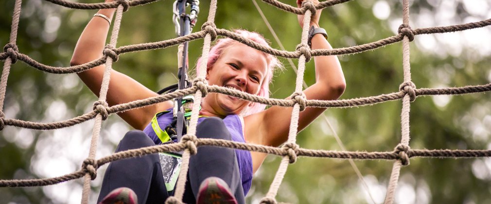 A person attached by harness moving along a cargo net