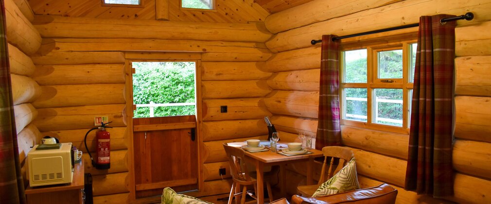 Interior of a wooden cabin showing back of sofa, kitchen area and half-open stable door