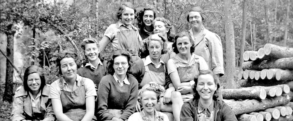 A group of women in the forest in front of a timber stack