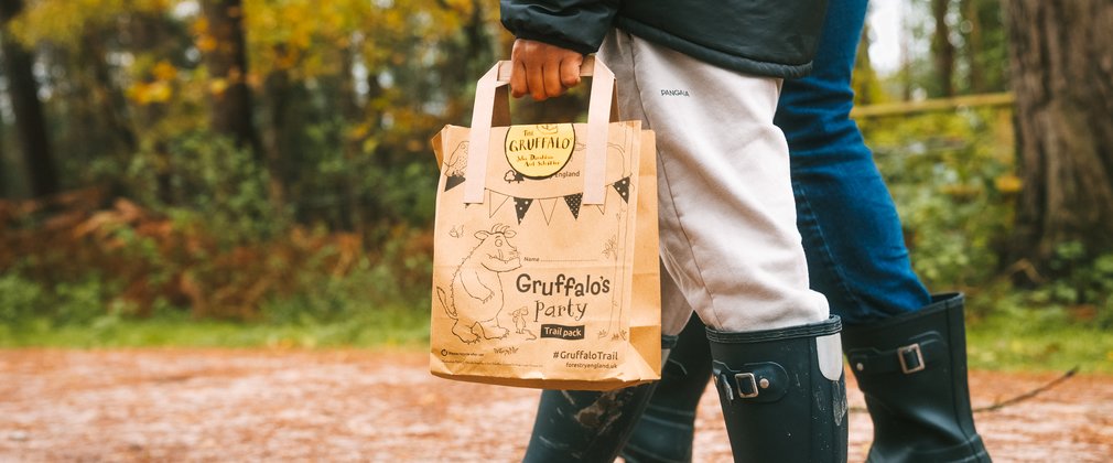 Shot of legs and wellies of two people walking through forest holding Gruffalo paper bag