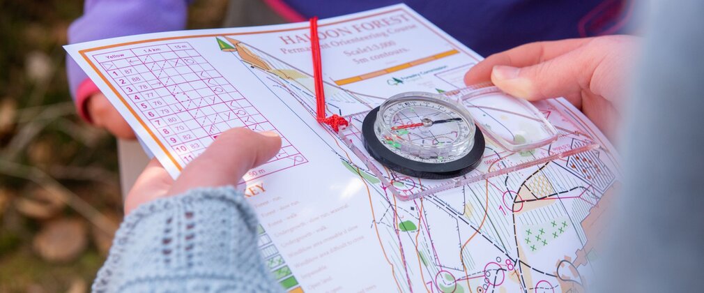 Close-up of hands holding a map and compass.