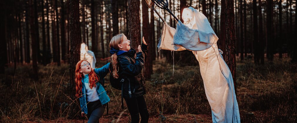 two children with a ghost model in a forest halloween activity