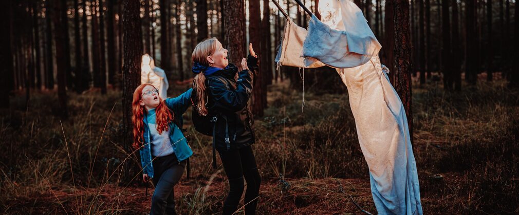 two children with a ghost model in a forest halloween activity
