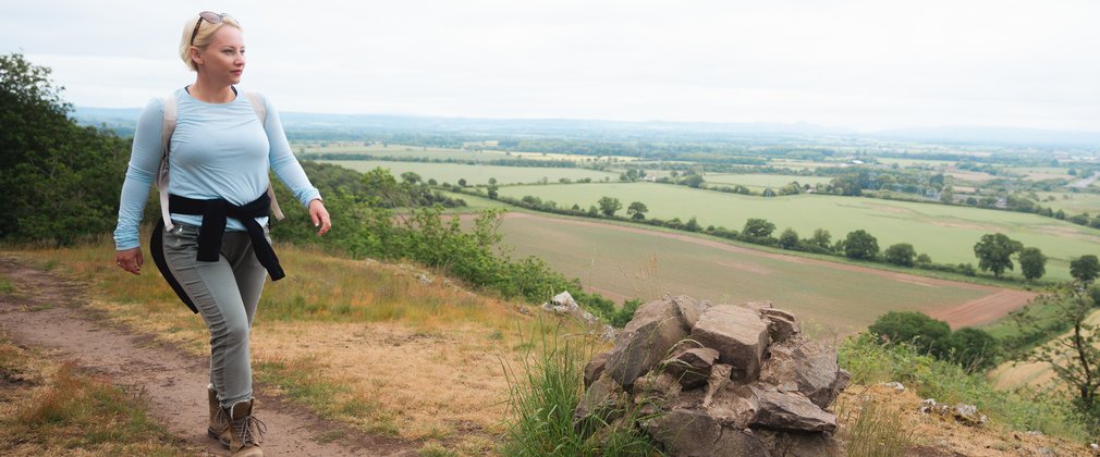 A women walking along a trail on a hillside, looking at the view