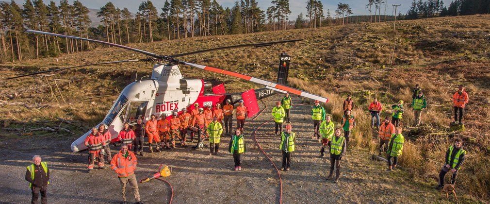 Staff standing by helicopter in forest clearing