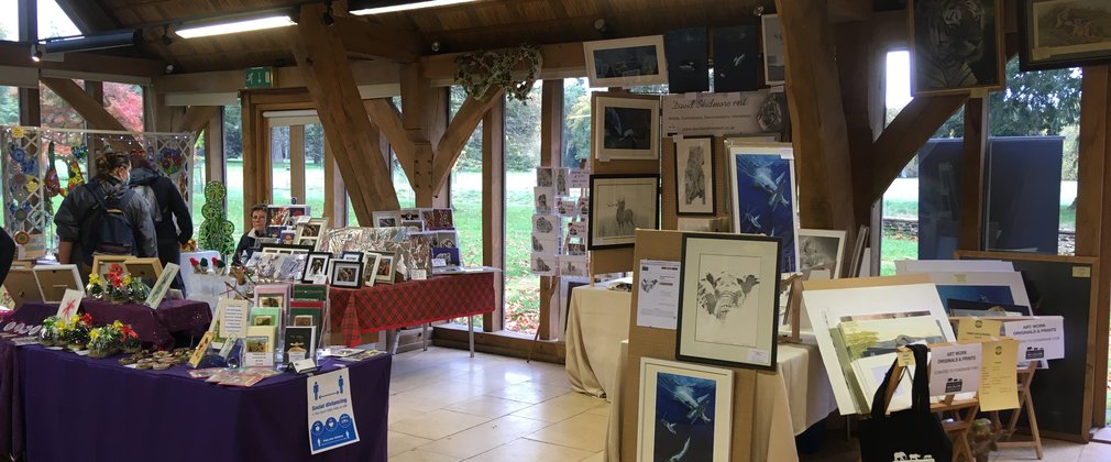Tables are set up in a hall space with art and crafts to sell to visitors.
