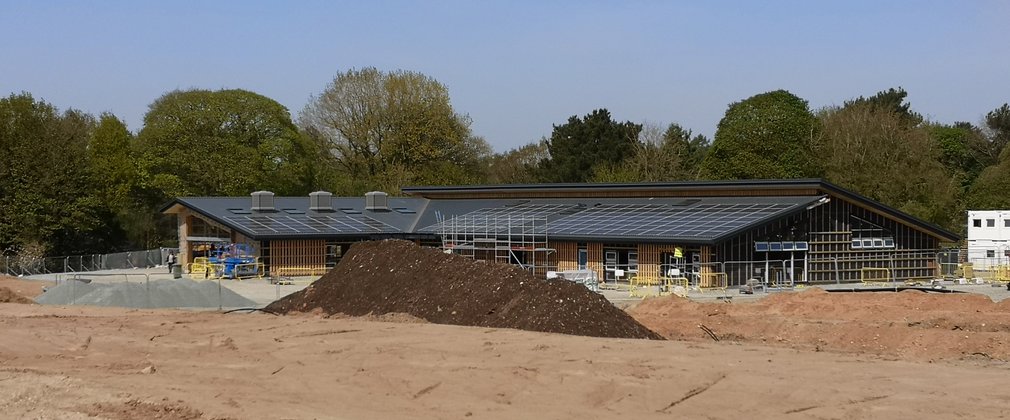 Construction site with mound of mud in front of a forest visitor centre