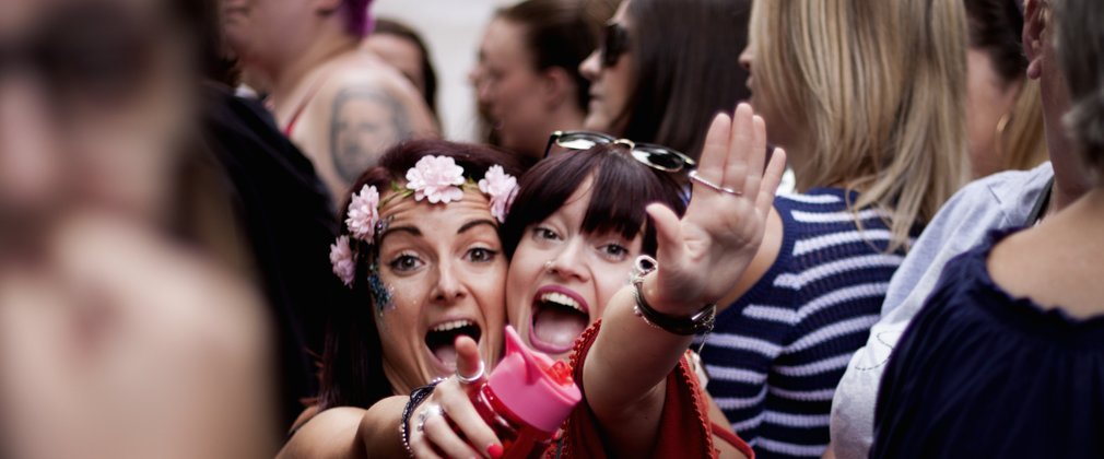 Two women pointing at the camera and smiling at a concert